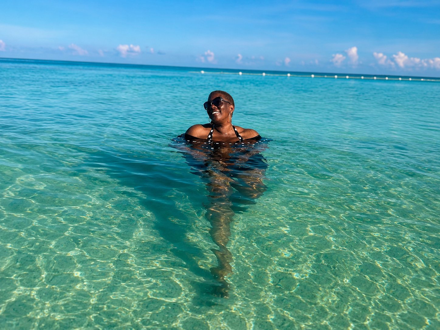 Carol enjoying clear turquoise ocean water while traveling.